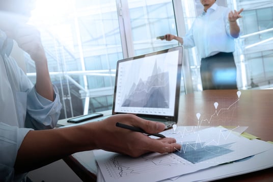 business documents on office table with smart phone and laptop computer and graph business with social network diagram and two colleagues discussing data in the background-1